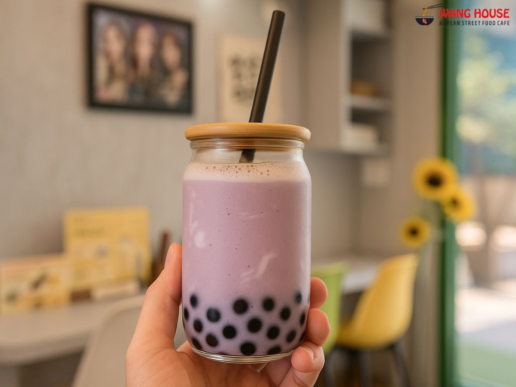 Strawberries and Cream boba tea in Delhi from The Wang House, Laxmi Nagar – A pastel pink milk tea served in a clear glass jar with a golden lid and black straw, topped with a light froth and filled with black tapioca pearls. The drink radiates a sweet, fruity aroma and creamy richness, set against a stylish background, capturing the essence of a refreshing Korean-style boba tea in East Delhi.
