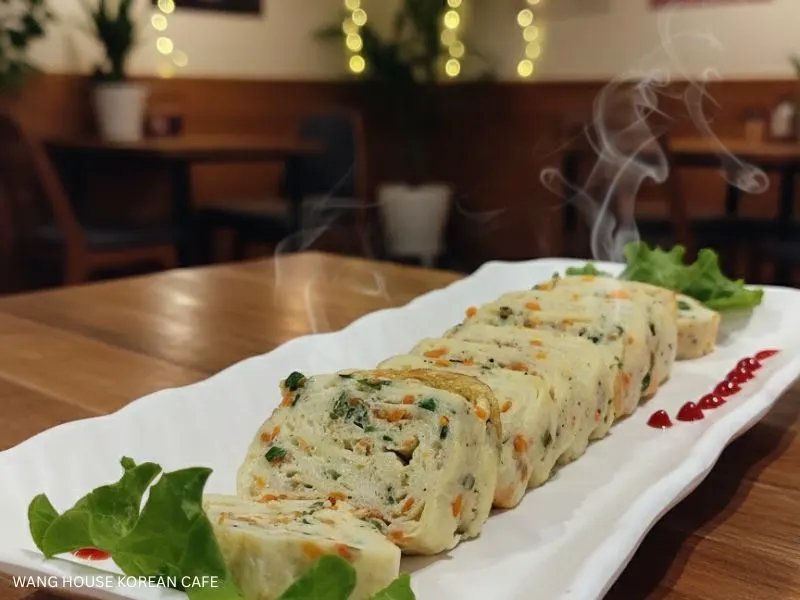 Best Korean Cafe: A close-up of a perfectly cooked omurice, drizzled with ketchup and garnished with fresh greens, ready to be enjoyed. Wang House Korean Cafe.